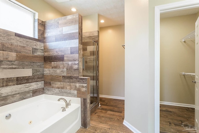 bathroom featuring a textured ceiling, wood-type flooring, and separate shower and tub