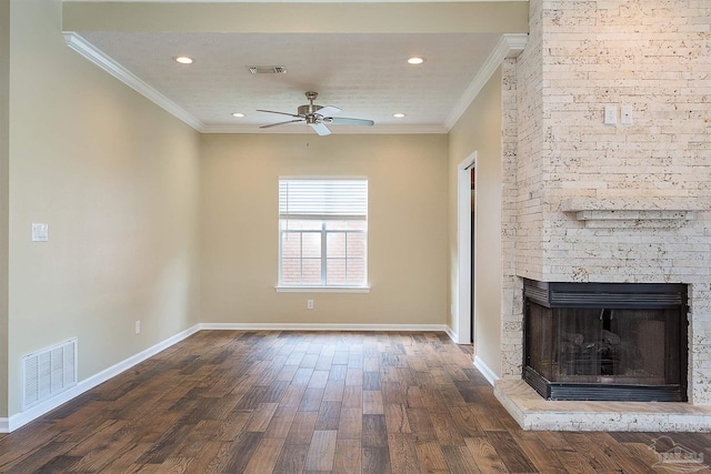 unfurnished living room featuring dark hardwood / wood-style flooring, crown molding, a large fireplace, and ceiling fan