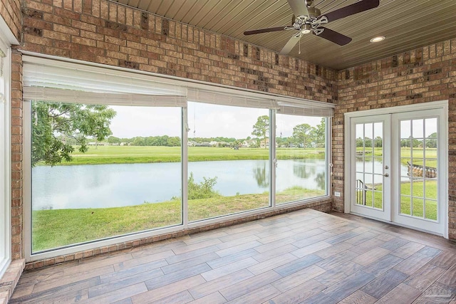 unfurnished sunroom with a water view, wooden ceiling, ceiling fan, and french doors