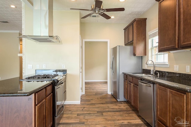 kitchen featuring dark stone countertops, sink, island range hood, and stainless steel appliances