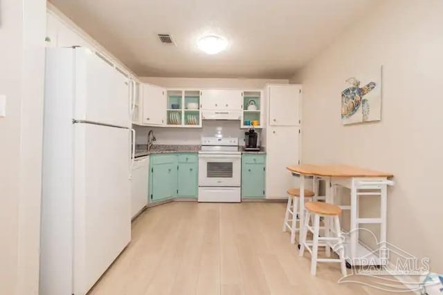 kitchen with white appliances, sink, light wood-type flooring, exhaust hood, and white cabinetry