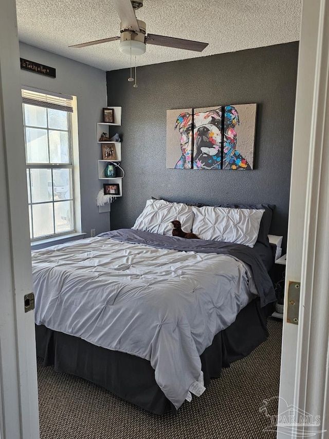 bedroom with ceiling fan, carpet, and a textured ceiling