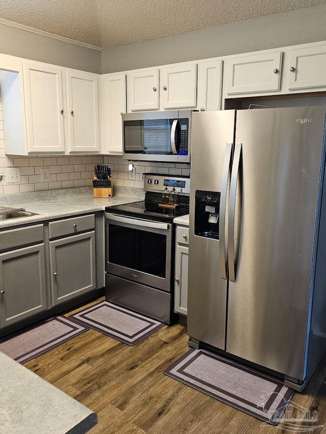 kitchen with white cabinets, appliances with stainless steel finishes, dark hardwood / wood-style flooring, and a textured ceiling