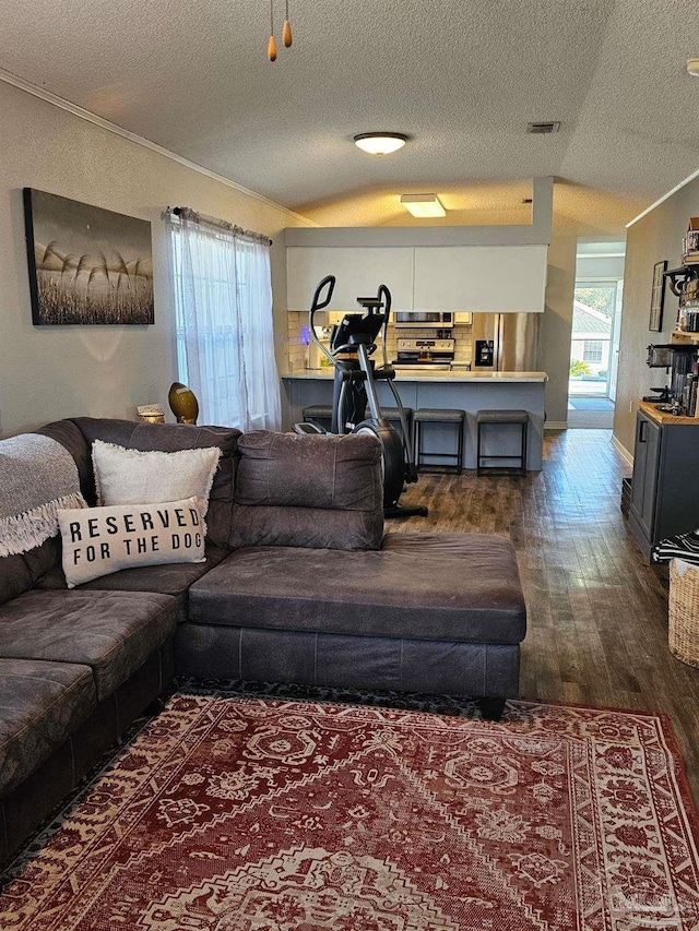 living room with a textured ceiling, dark hardwood / wood-style flooring, vaulted ceiling, and ornamental molding