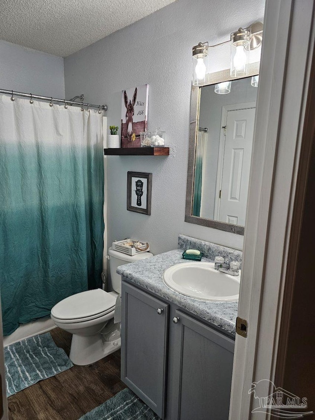 bathroom with toilet, vanity, walk in shower, hardwood / wood-style floors, and a textured ceiling