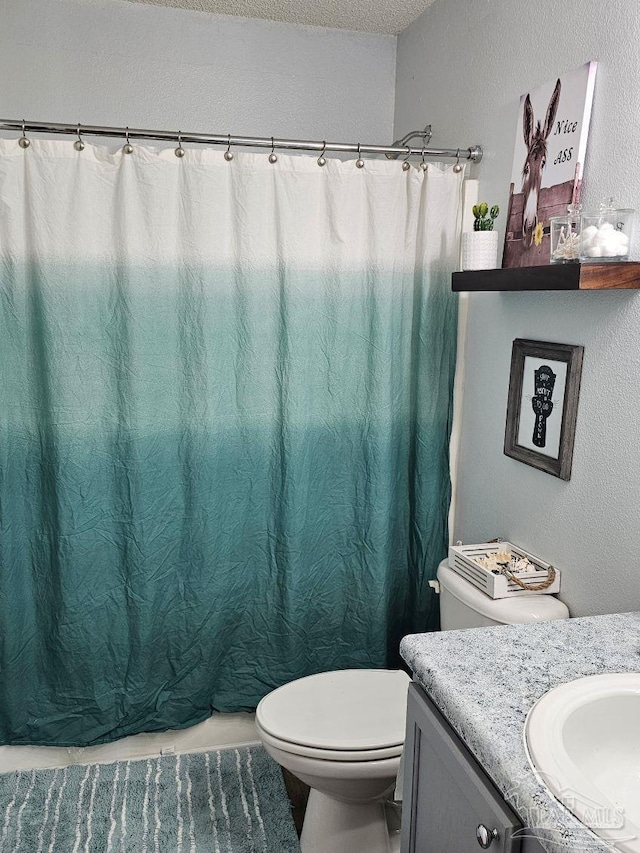 bathroom featuring toilet, a textured ceiling, and vanity