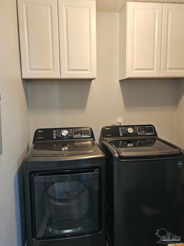 washroom with washing machine and dryer, a textured ceiling, and cabinets