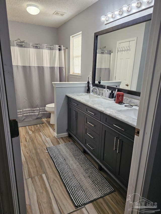 bathroom with hardwood / wood-style flooring, a textured ceiling, toilet, and vanity