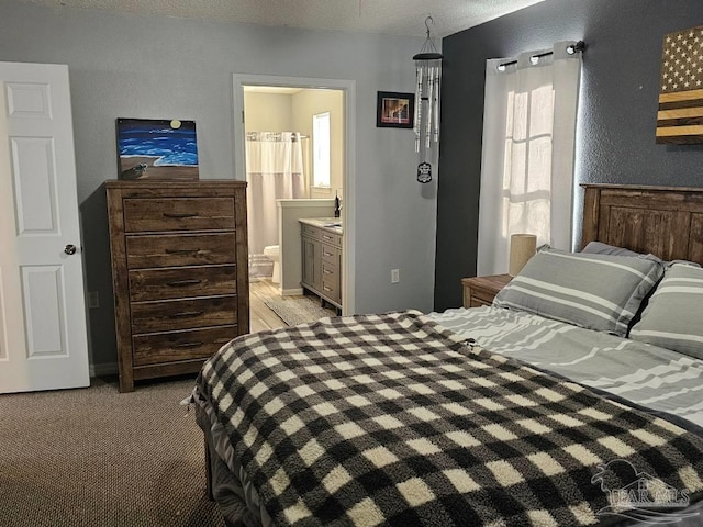 carpeted bedroom with ensuite bathroom and a textured ceiling