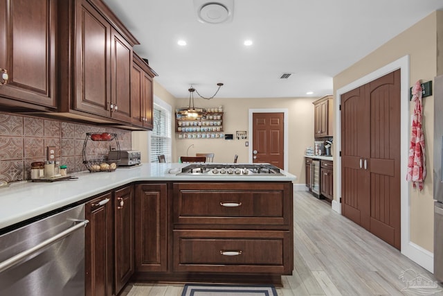 kitchen featuring hanging light fixtures, appliances with stainless steel finishes, backsplash, and kitchen peninsula