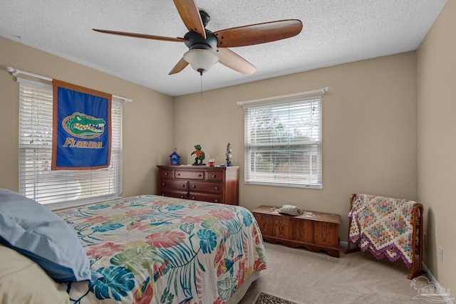 carpeted bedroom featuring ceiling fan and a textured ceiling