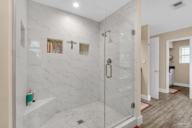 bathroom with a shower with door and hardwood / wood-style floors