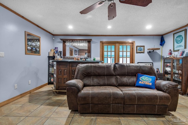 living room featuring indoor bar, ornamental molding, ceiling fan, tile patterned floors, and a textured ceiling