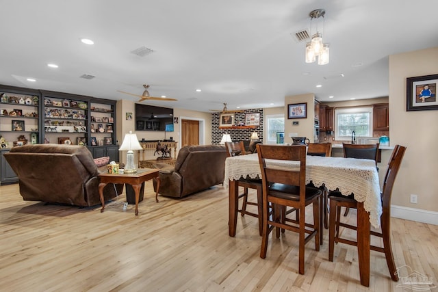 dining room with a brick fireplace and light hardwood / wood-style flooring