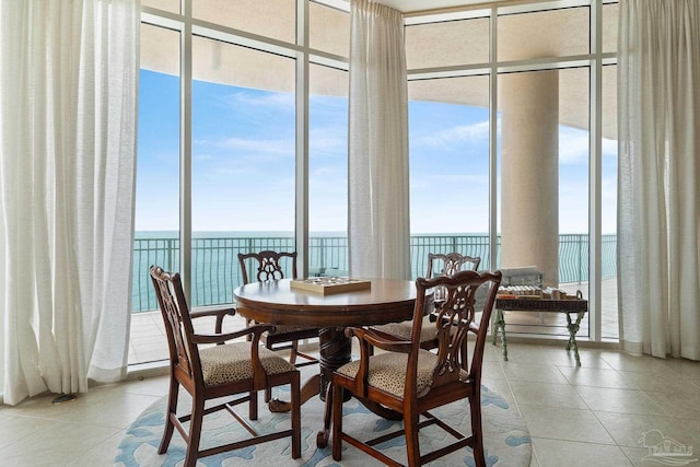 tiled dining area featuring a water view and expansive windows