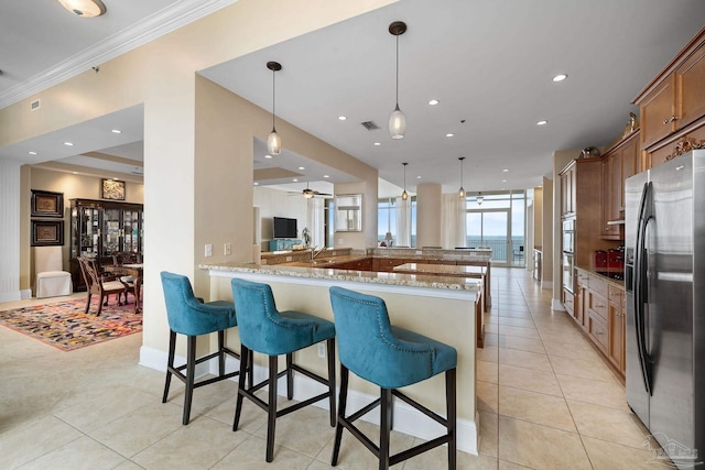 kitchen featuring kitchen peninsula, appliances with stainless steel finishes, light stone counters, crown molding, and decorative light fixtures