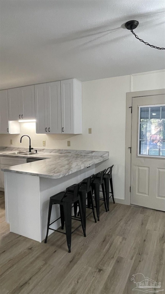 kitchen with kitchen peninsula, white cabinets, and a breakfast bar