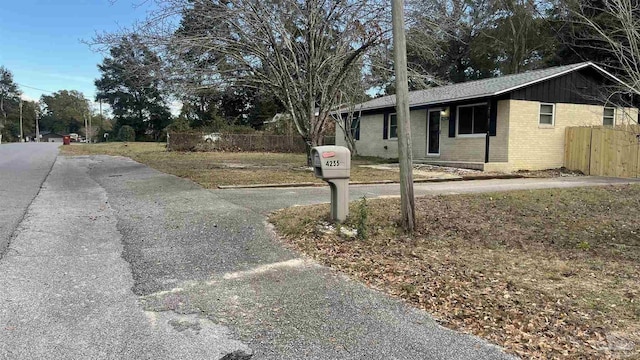 exterior space featuring fence, brick siding, and roof with shingles