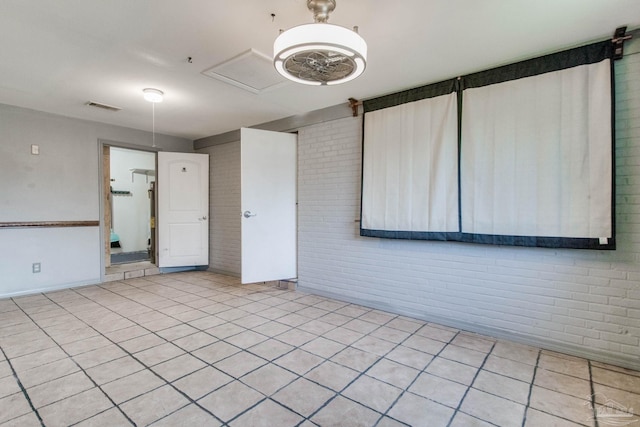 empty room with light tile patterned floors and brick wall