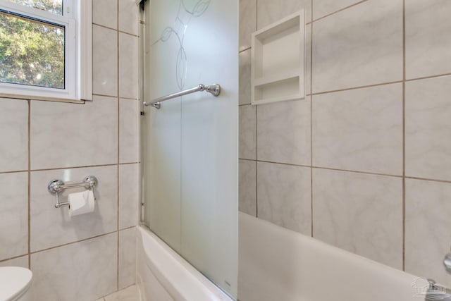 bathroom featuring toilet and tiled shower / bath