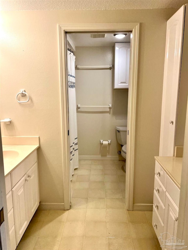 bathroom with toilet, vanity, a textured ceiling, and tile patterned floors