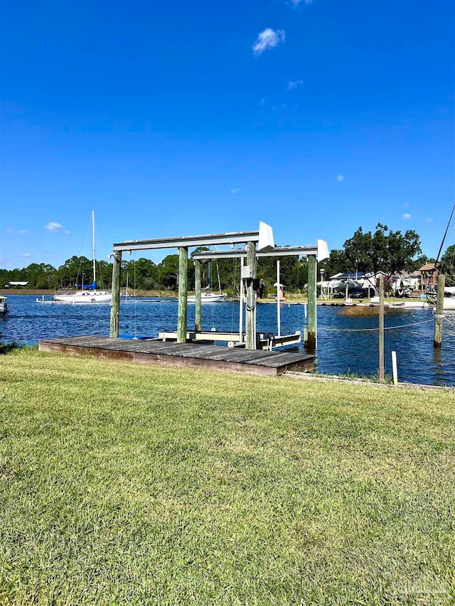 view of dock with a water view and a lawn