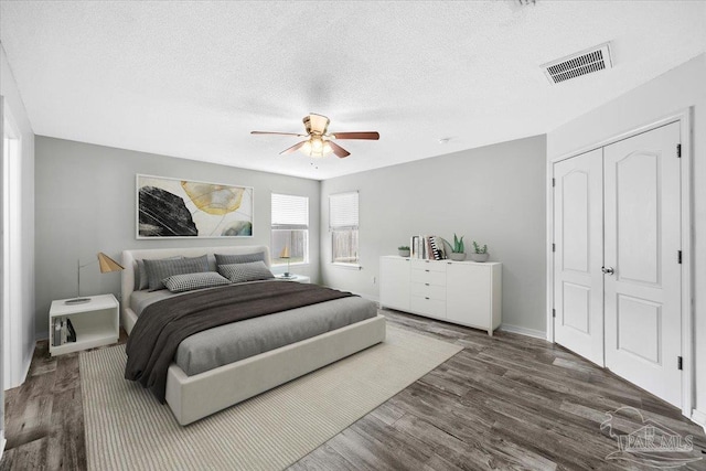 bedroom featuring ceiling fan, a closet, dark hardwood / wood-style floors, and a textured ceiling