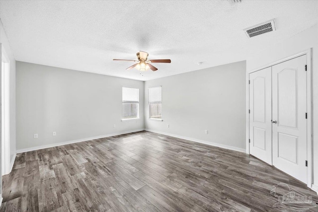 spare room featuring dark hardwood / wood-style flooring, ceiling fan, and a textured ceiling