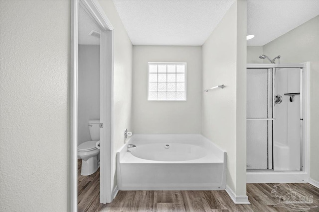 bathroom featuring independent shower and bath, hardwood / wood-style floors, a textured ceiling, and toilet