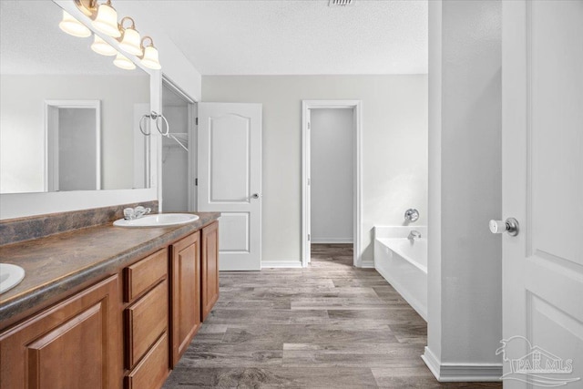 bathroom featuring hardwood / wood-style flooring, vanity, a bathing tub, and a textured ceiling