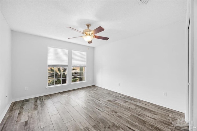 empty room with wood-type flooring, ceiling fan, and a textured ceiling