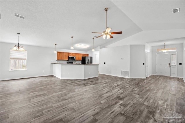 unfurnished living room with dark wood-type flooring, ceiling fan, vaulted ceiling, and a textured ceiling