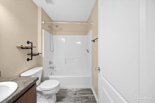 full bathroom featuring hardwood / wood-style floors, shower / bathtub combination, vanity, toilet, and a textured ceiling