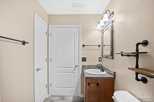 bathroom featuring vanity, a textured ceiling, and toilet