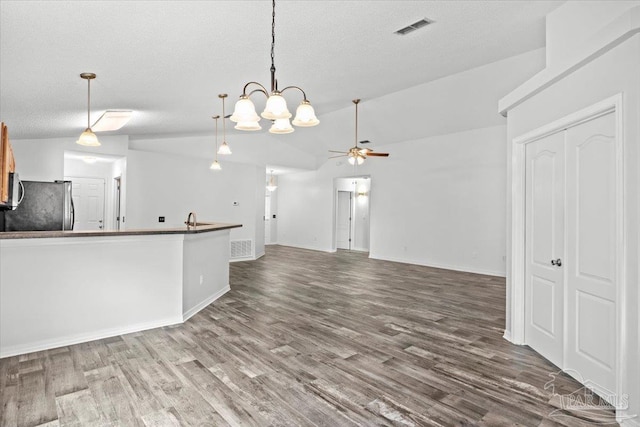 unfurnished living room with lofted ceiling, sink, a textured ceiling, ceiling fan, and hardwood / wood-style floors