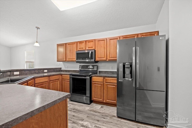 kitchen with sink, decorative light fixtures, a textured ceiling, light wood-type flooring, and stainless steel appliances