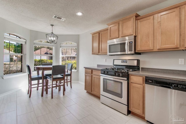 kitchen featuring stainless steel appliances, a notable chandelier, visible vents, and a healthy amount of sunlight