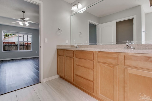 bathroom featuring a sink, double vanity, baseboards, and ceiling fan