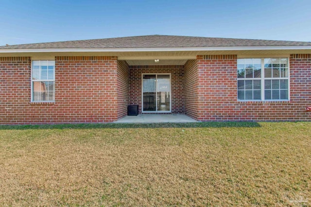 back of property featuring brick siding and a lawn