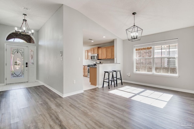 foyer entrance featuring visible vents, baseboards, an inviting chandelier, and wood finished floors