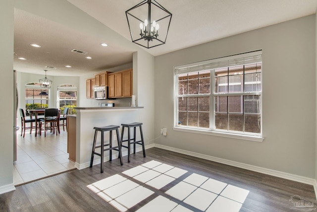 kitchen with stainless steel microwave, a notable chandelier, baseboards, and visible vents