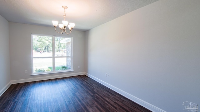 spare room with dark hardwood / wood-style flooring, a textured ceiling, and a chandelier