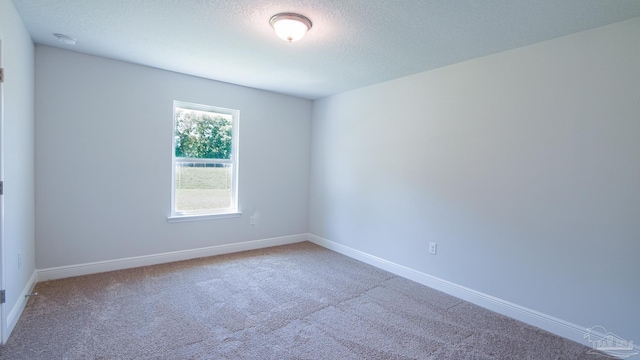 carpeted empty room featuring a textured ceiling