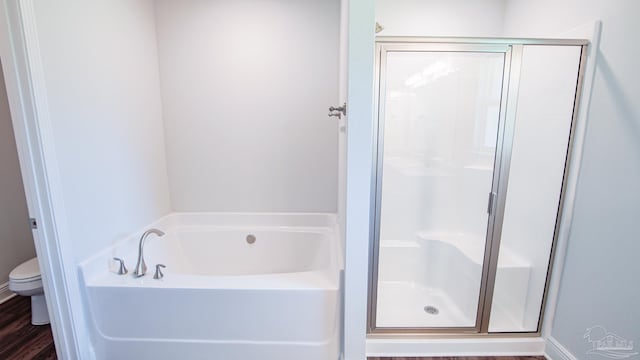 bathroom with toilet, separate shower and tub, and hardwood / wood-style floors