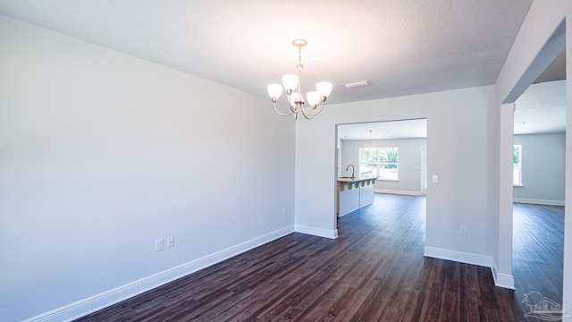 unfurnished dining area featuring dark hardwood / wood-style flooring, sink, and a notable chandelier