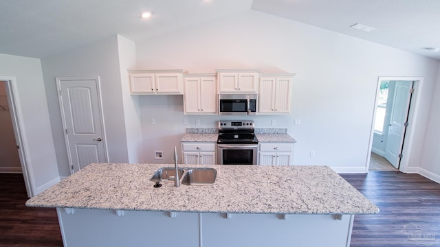 kitchen with appliances with stainless steel finishes, white cabinetry, sink, a breakfast bar area, and a center island with sink