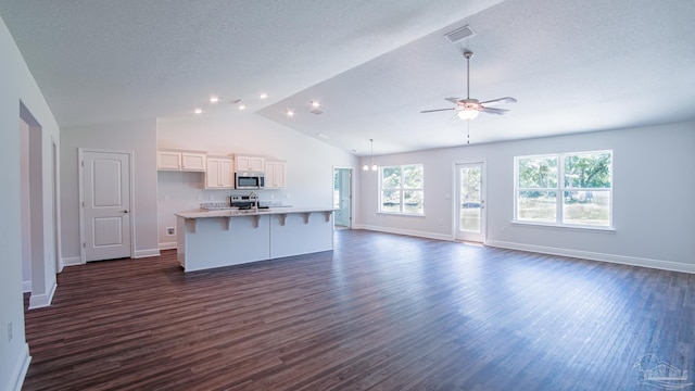 unfurnished living room with dark wood-type flooring, ceiling fan, lofted ceiling, and a textured ceiling