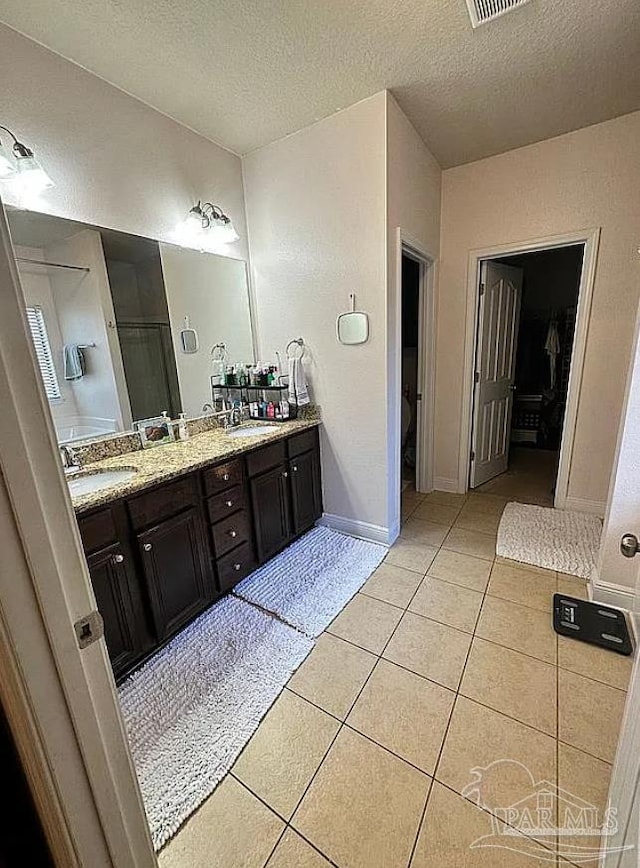 bathroom with vanity, a shower, a textured ceiling, and tile patterned floors