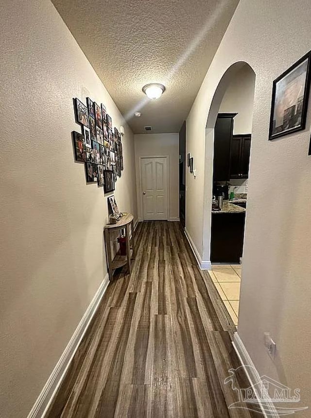 hall with dark hardwood / wood-style floors and a textured ceiling