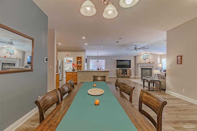 dining area featuring a fireplace, light hardwood / wood-style flooring, and lofted ceiling